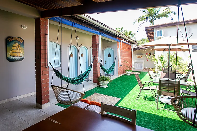 Pátio da Pousada Petit Refuge com redes armadas e as portas azuis dos apartamentos