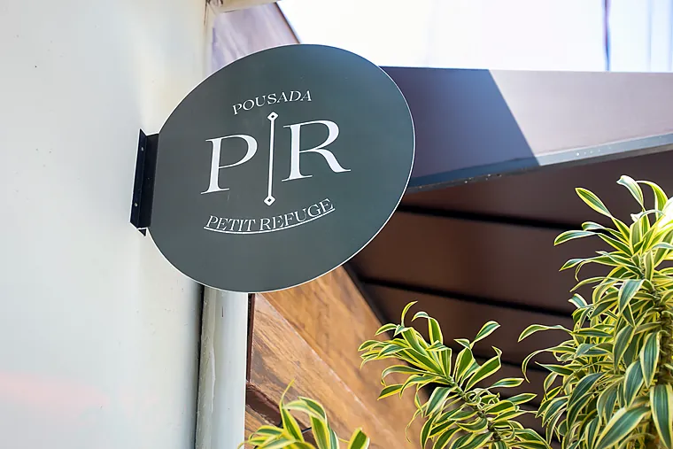 Placa da Pousada Petit Refuge com o monograma PR na entrada da pousada