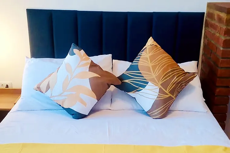 Cabeceira estofada azul-marinho da cama de casal no Junior com vista para o jardim da Pousada Petit Refuge