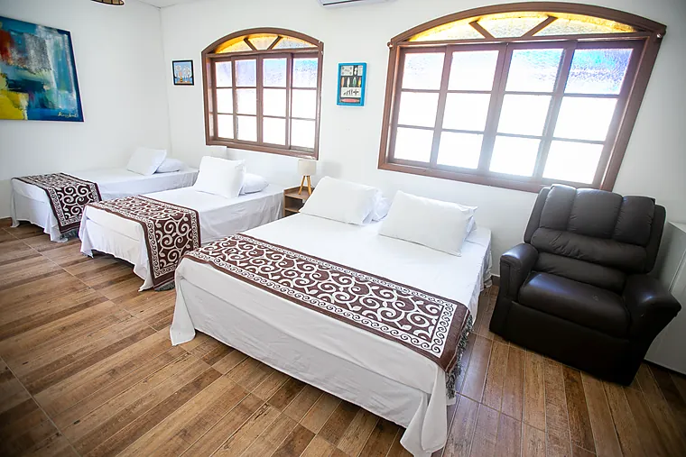 Suíte Júnior da Pousada Petit Refuge com cama de casal, duas camas de solteiro e poltrona reclinável