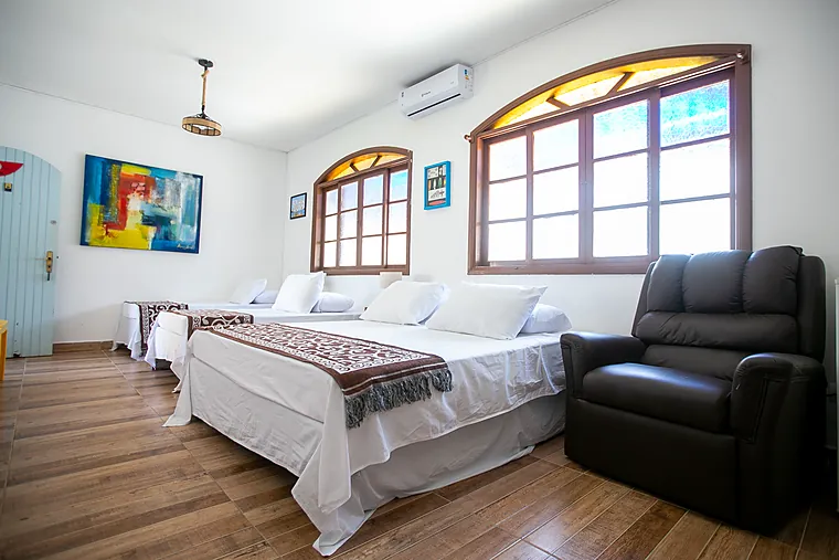 Camas da Suíte Júnior da Petit Refuge com janelas arqueadas de vitral ao fundo